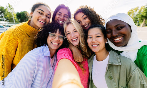 Multiracial group of seven cheerful women having fun taking selfie portrait. Female friendship concept with millennial girls enjoying free time at city street. Integration and happy people concept #724044177