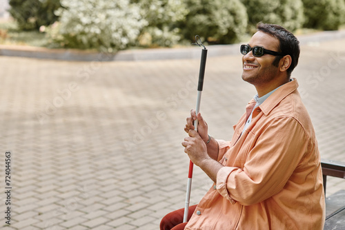 Cuadro en lienzo merry indian blind man in orange jacket sitting outside on bench with walking st