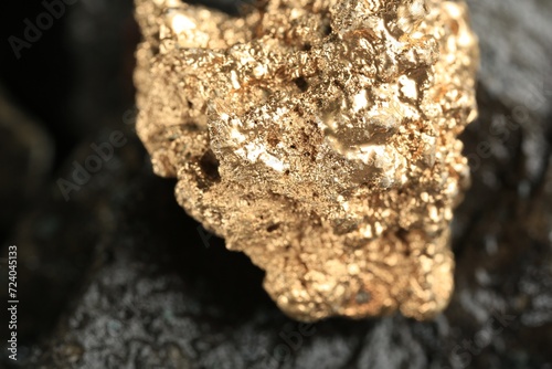 Shiny gold nugget on grey stone, closeup