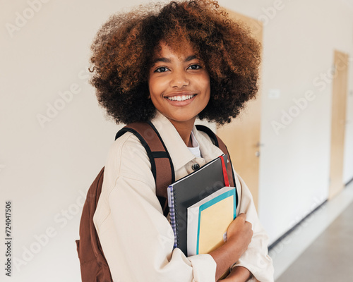 Student girl with books smiling while looking at the camera