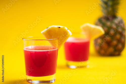 Pineapple juice in glass closeup near sliced fruit with spash and dripping liqid for summer vibes photo