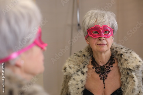 Seductive senior woman getting ready for a masquerade party 