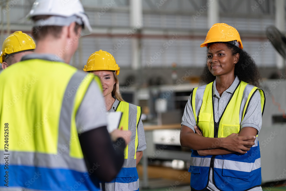 Portrait confident African American businesswoman with team working with machine at factory Portrait confident African American businesswoman with team working with machine at factory