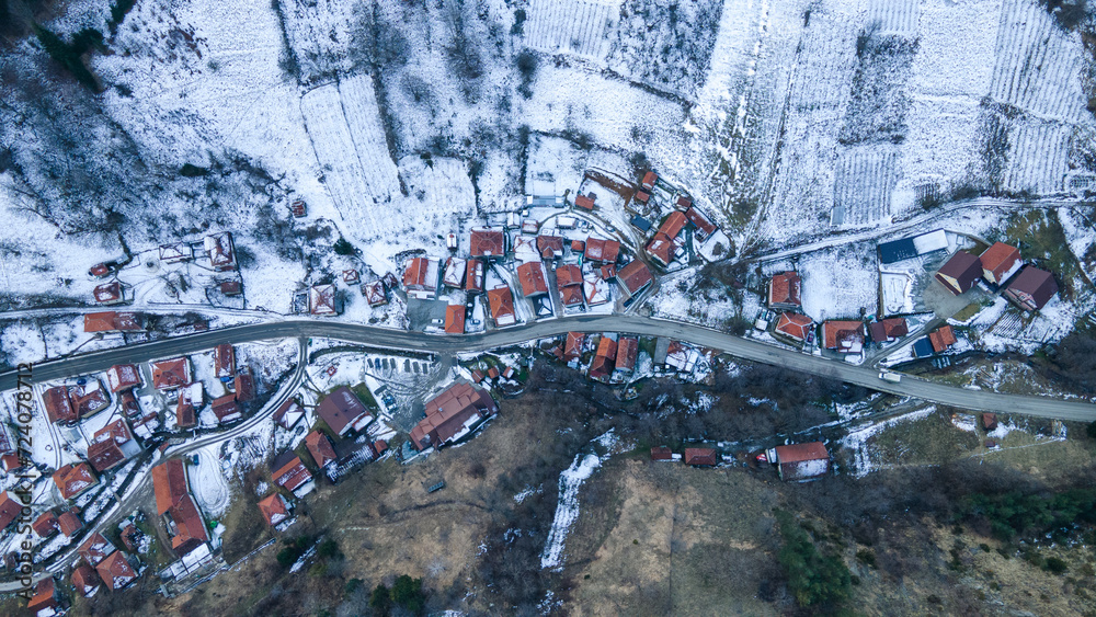 Drone view of Brzece on Kopaonik with snow on the north side of the mountain and green grass in the sun.