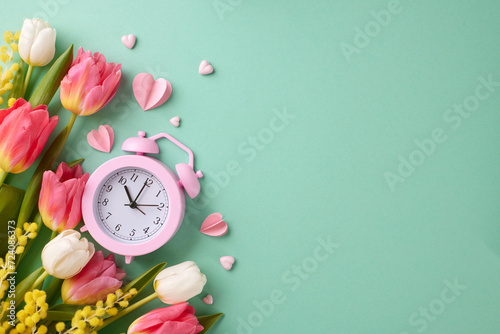 A spring affair: prepare to March 8th in celebration of women. Top view photo of alarm clock, tulips, mimosa, hearts on turquoise background with advert area photo
