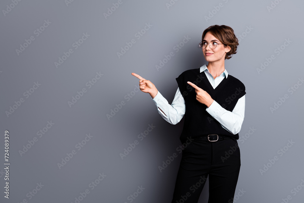 Photo of happy dreamy woman coach wear black waistcoat spectacles showing two fingers looking empty space isolated grey color background Photo of happy dreamy woman coach wear black waistcoat spectacles showing two fingers looking empty space isolated grey color background
