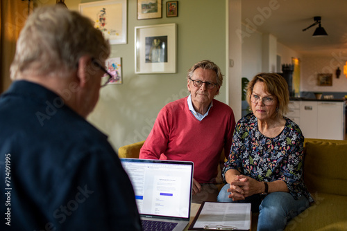 Worried senior couple talking to their financial advisor at home photo