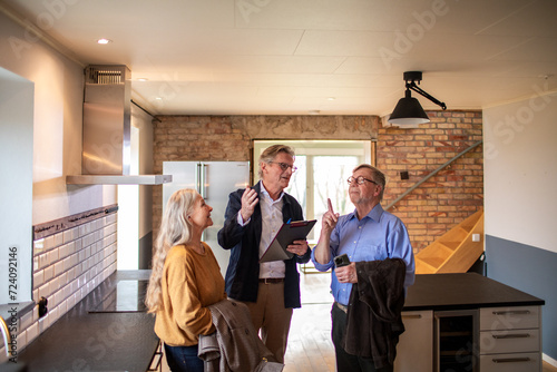 Senior couple looking at a house for purchase or lease with their real estate agent photo