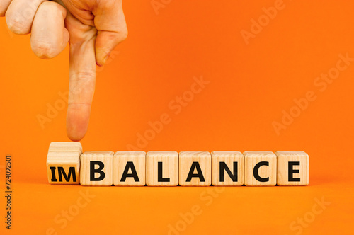 Balance or imbalance symbol. Concept word Imbalance or Balance on beautiful wooden cubes. Beautiful orange background. Businessman hand. Business balance or imbalance concept. Copy space.