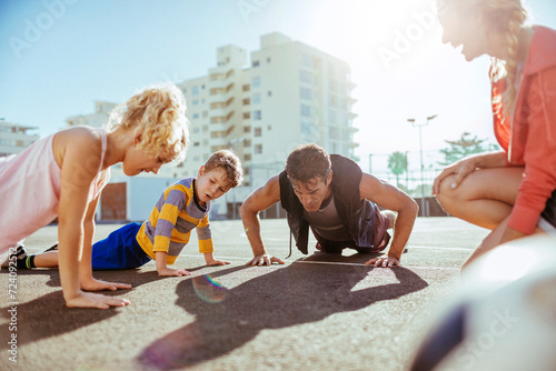 Young family doing push ups and exercising on an outdoor sports court photo