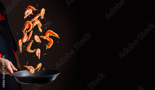 cooking shrimp in pan. Chef cooking prawn on a dark background. copy space for text