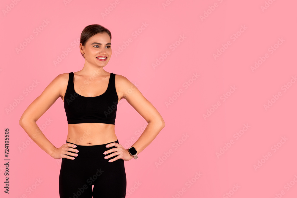 Smiling woman dressed in black workout clothes standing with hands on hips Smiling woman dressed in black workout clothes standing with hands on hips