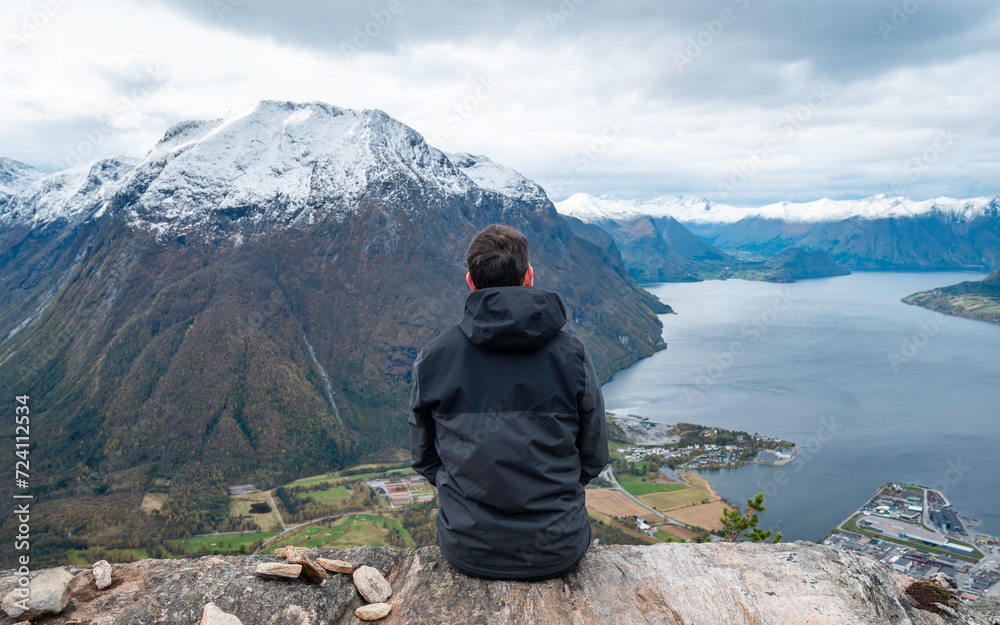 Traveler with his back turned, hands open, enjoying a mountain landscape in the Norwegian fjords of the city of Andalsnes, Norway. Traveler with his back turned, hands open, enjoying a mountain landscape in the Norwegian fjords of the city of Andalsnes, Norway.