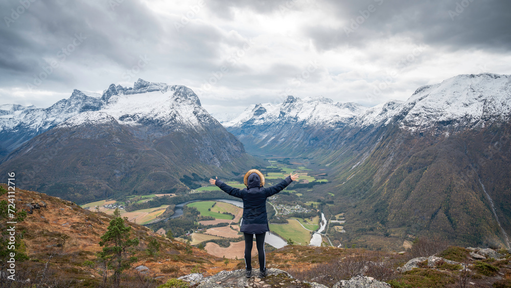 Traveler with his back turned, hands open, enjoying a mountain landscape in the Norwegian fjords of the city of Andalsnes, Norway.
