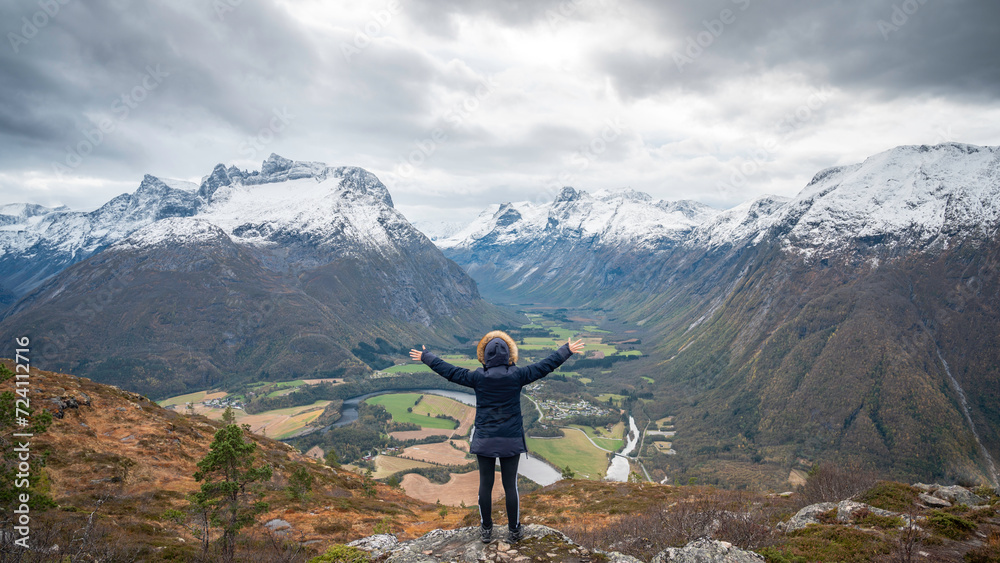 Traveler with his back turned, hands open, enjoying a mountain landscape in the Norwegian fjords of the city of Andalsnes, Norway. Traveler with his back turned, hands open, enjoying a mountain landscape in the Norwegian fjords of the city of Andalsnes, Norway.