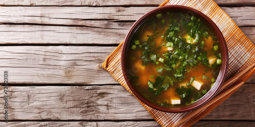 Miso Soup with Tofu and Chives. Traditional Japanese miso soup with soft tofu cubes and chopped chives in a rustic earthenware bowl, copy space. photo