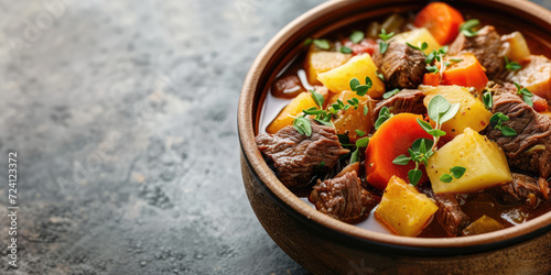 Savory Beef Stew with Potatoes and Carrots. Rich beef stew with tender chunks of meat, potatoes, and carrots, garnished with fresh thyme, copy space.