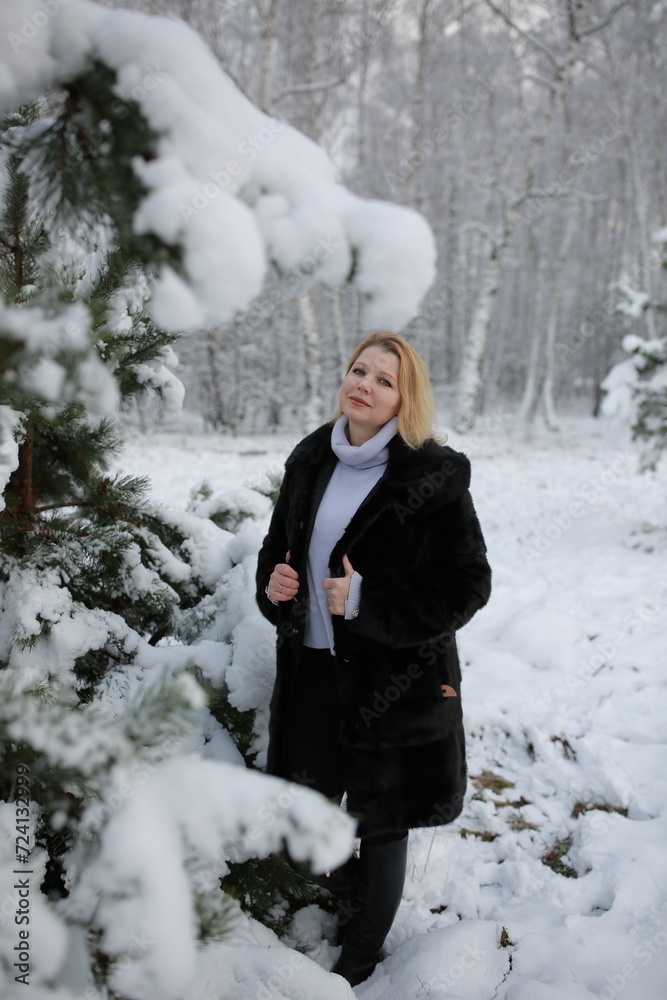 beautiful forty-year-old woman in a snowy forest. a woman in a fur black fur coat in winter in the forest. middle-aged woman near snowy trees beautiful forty-year-old woman in a snowy forest. a woman in a fur black fur coat in winter in the forest. middle-aged woman near snowy trees
