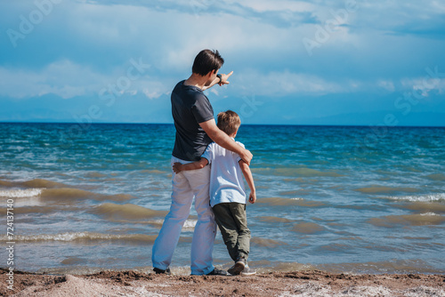 Father and son standing on the shore of the lake and looking away