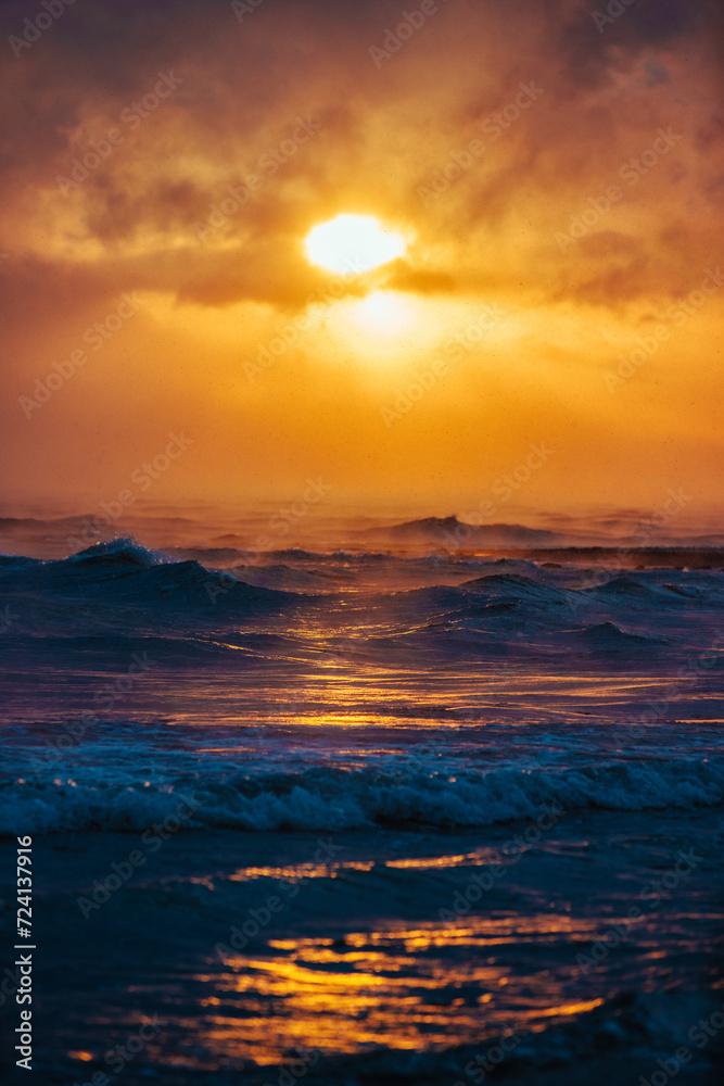Picturesque seascape during storm with snow at winter sunset