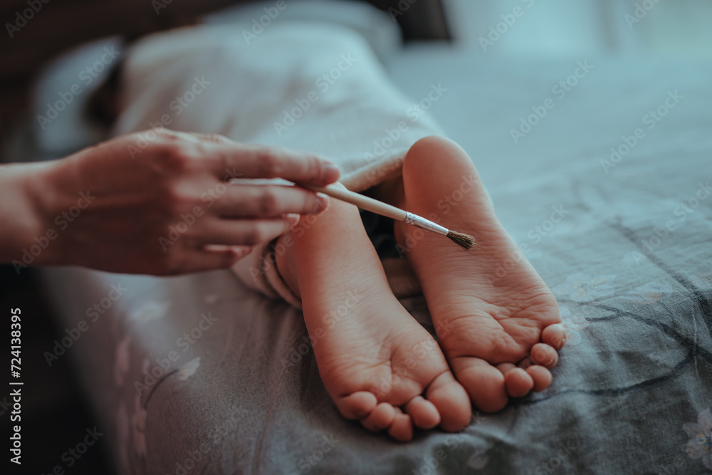 Woman's hand brushes feet of sleeping baby Woman's hand brushes feet of sleeping baby