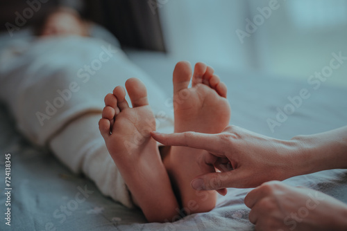 Woman's hand touches foot of sleeping child photo