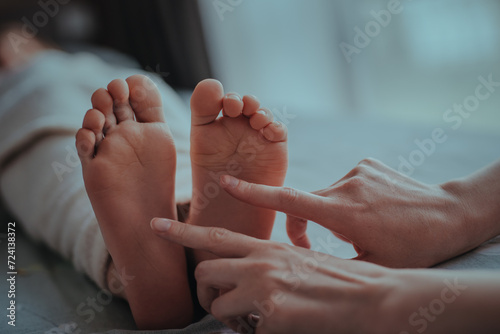 Mother tickles sleeping child feet