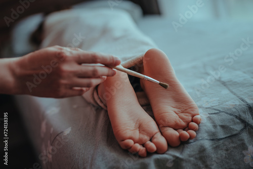 Woman's hand brushes feet of sleeping baby photo