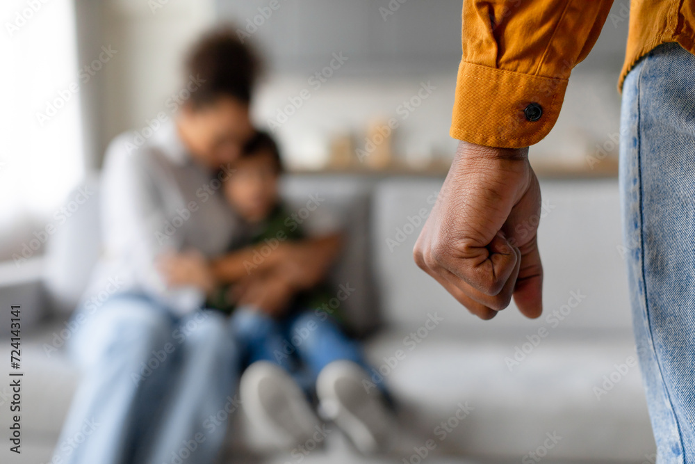 Father's clenched fist with mother and child blurred in background Father's clenched fist with mother and child blurred in background