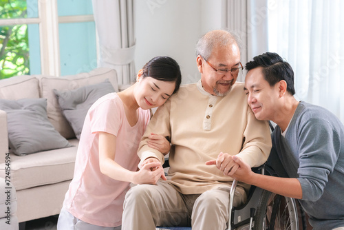 Happy elder Asian man using wheelchair while exercise indoor house with his son taking care of him at the retirement age with copy space © chokniti