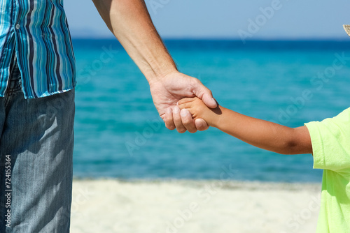A Hands of a happy parent and child on the seashore on a journey trip in nature