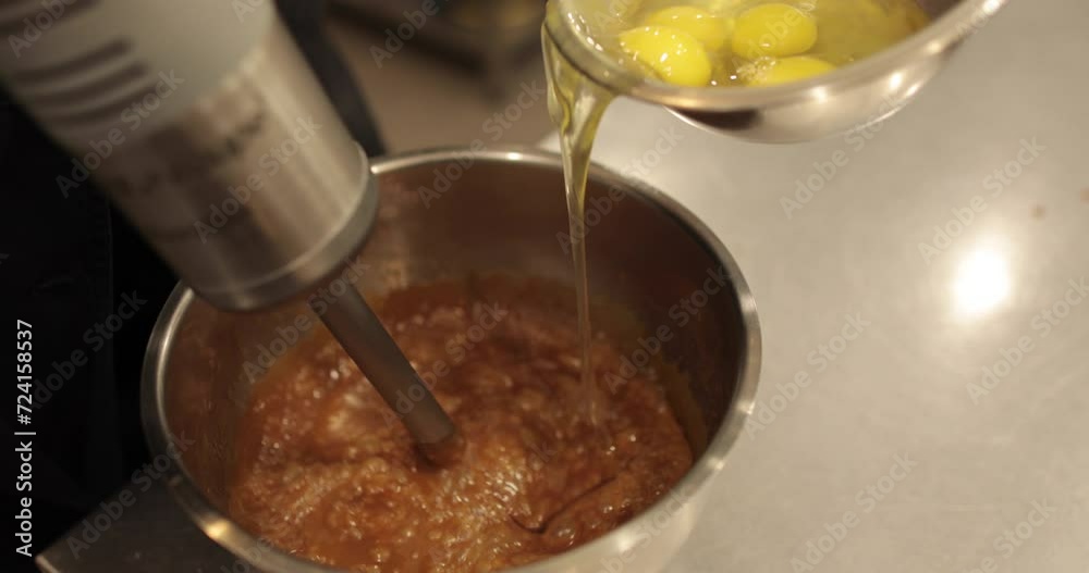 Mixing the chocolate glaze in a round metal bowl with a whisk. Close-up of hands stirring chocolate mousse with a whisk. Professional confectionery. Mixing the chocolate glaze in a round metal bowl with a whisk. Close-up of hands stirring chocolate mousse with a whisk. Professional confectionery.