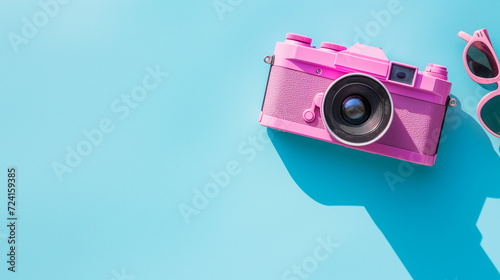 Retro pink camera and sunglasses with a blue shadow, suitable for travel blogs, photography tutorials, and summer fashion promos