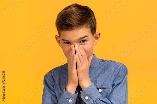 Teen boy with look of disgust pinching nose to avoid bad smell photo