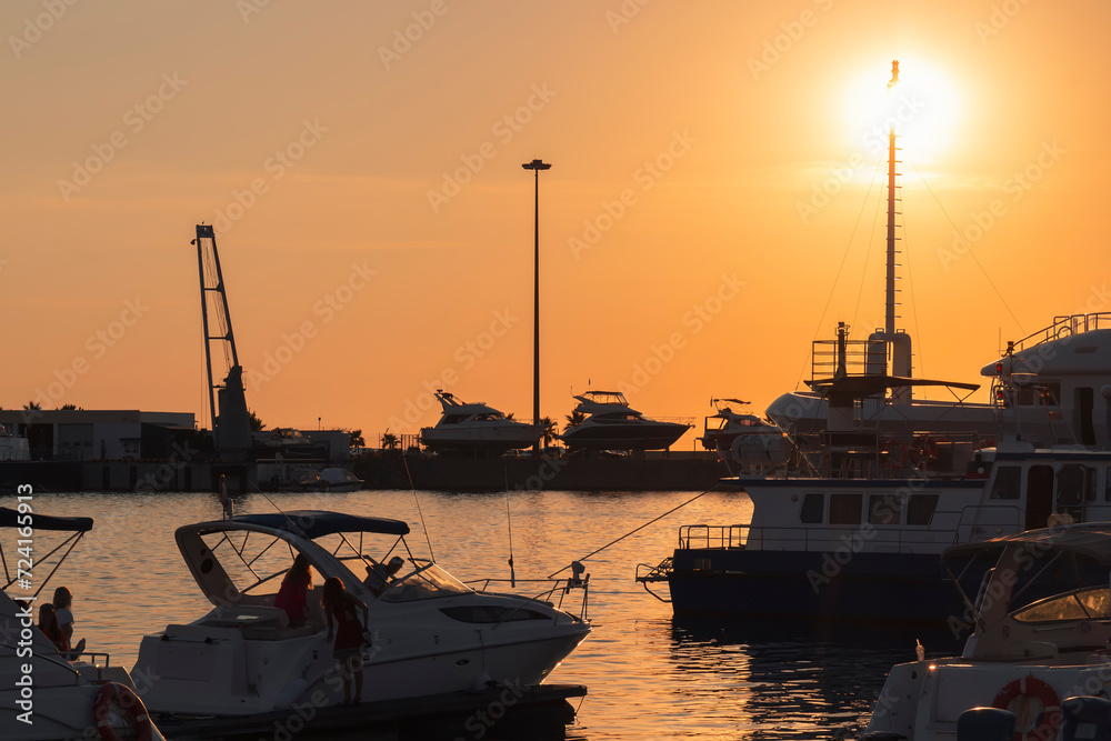 Fototapeta premium Yachts and boats moored at the seaport against a colorful sunset. The seaport of Sochi. 
