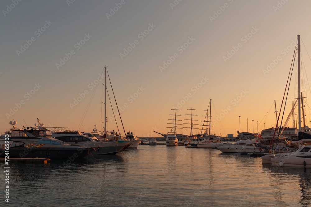 Yachts and boats moored at the seaport against a colorful sunset. The seaport of Sochi. 