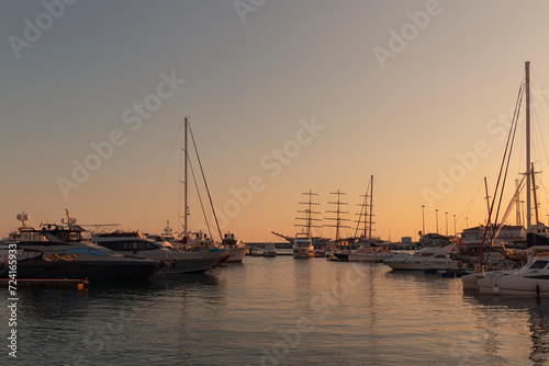Yachts and boats moored at the seaport against a colorful sunset. The seaport of Sochi. 