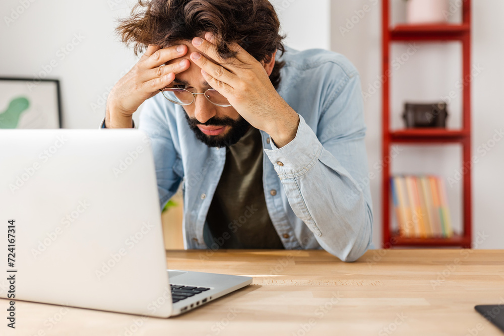 Exhausted young man reading bad news on laptop message. Exhausted young man reading bad news on laptop message.