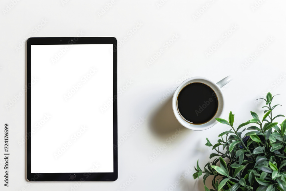 Empty electronic tablet on a table next to a cup of coffee and a plant. Use as a template or mockup Empty electronic tablet on a table next to a cup of coffee and a plant. Use as a template or mockup