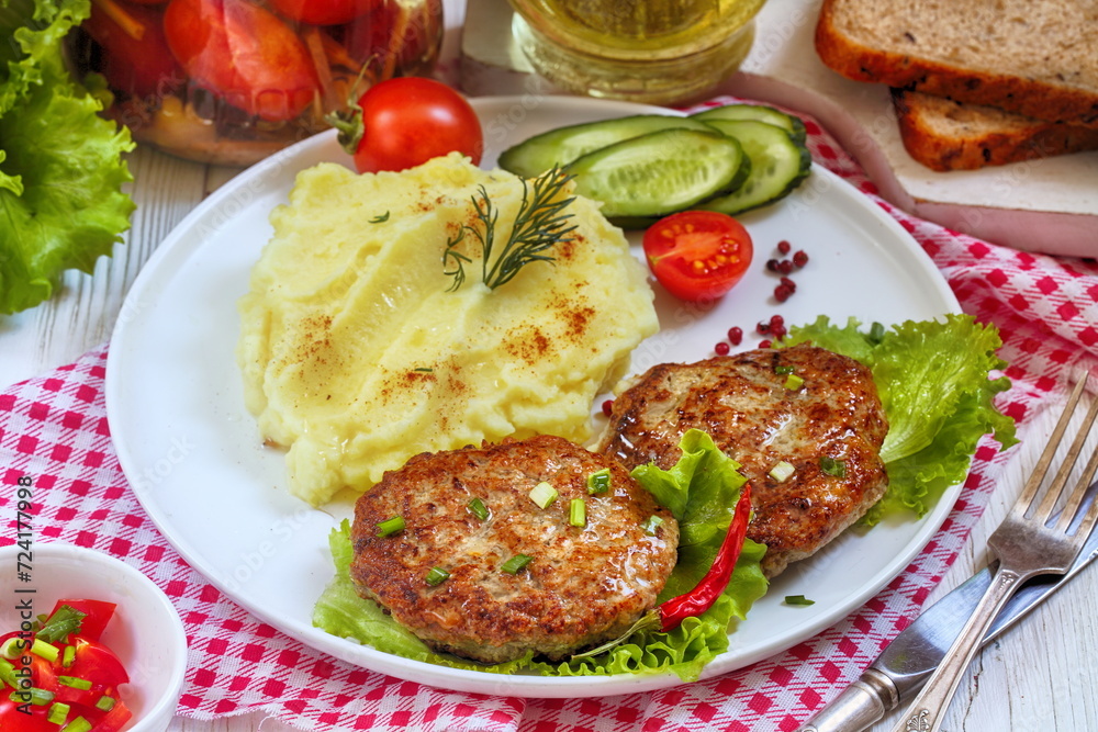 Cutlets with mashed potatoes in a plate on a checkered tablecloth