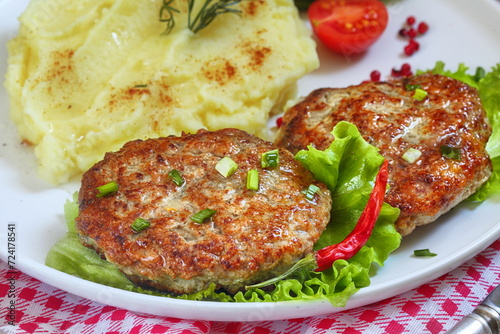 Cutlets with mashed potatoes in a plate on a checkered tablecloth