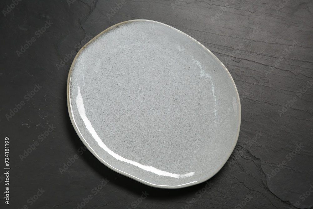 One ceramic plate on black textured table, top view One ceramic plate on black textured table, top view