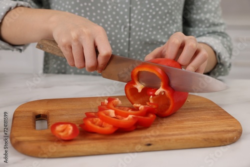 Cooking process. Woman cutting bell pepper at white countertop, closeup
