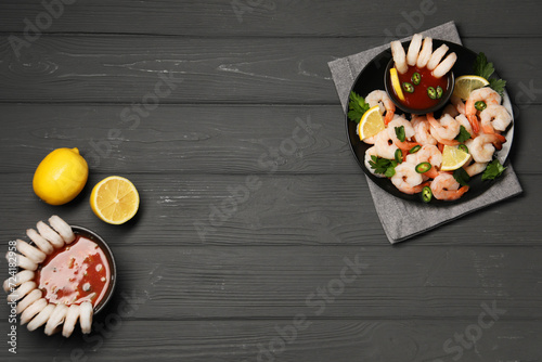 Tasty boiled shrimps with cocktail sauce, chili, parsley and lemon on grey wooden table, flat lay. Space for text