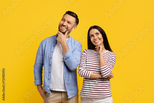 Portrait of pensive smiling couple standing against bright yellow background
