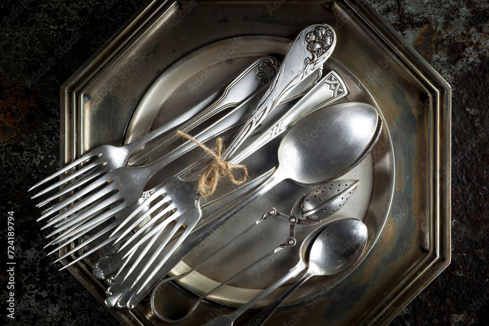 Antique silver cutlery on a dark background in a composition on a table. Antique silver cutlery on a dark background in a composition on a table.