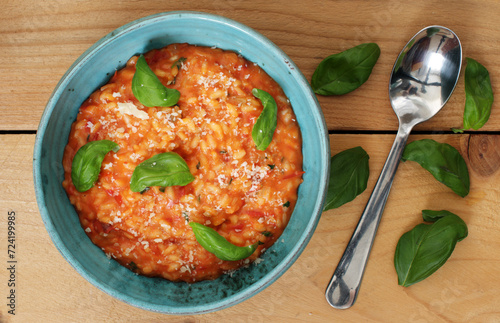 Delicious tomato risotto in bowl with basil on a wooden table