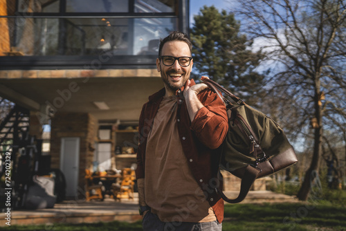 Portrait of one man happy caucasian male with travel bag at his house