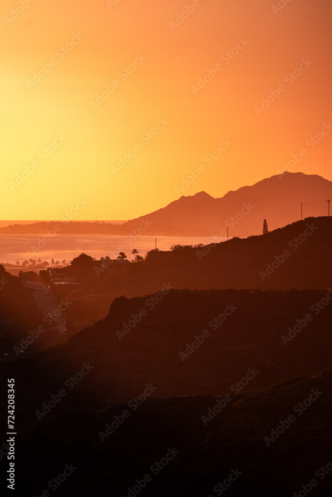 Vertical shot of a bright sunset sky over verdant hills in O'ahu, Hawaii