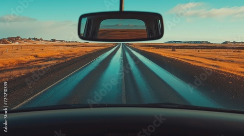 a car driving on the road, with the rearview mirror reflecting the surrounding scenery, illustrating the journey and constant vigilance of the driver.